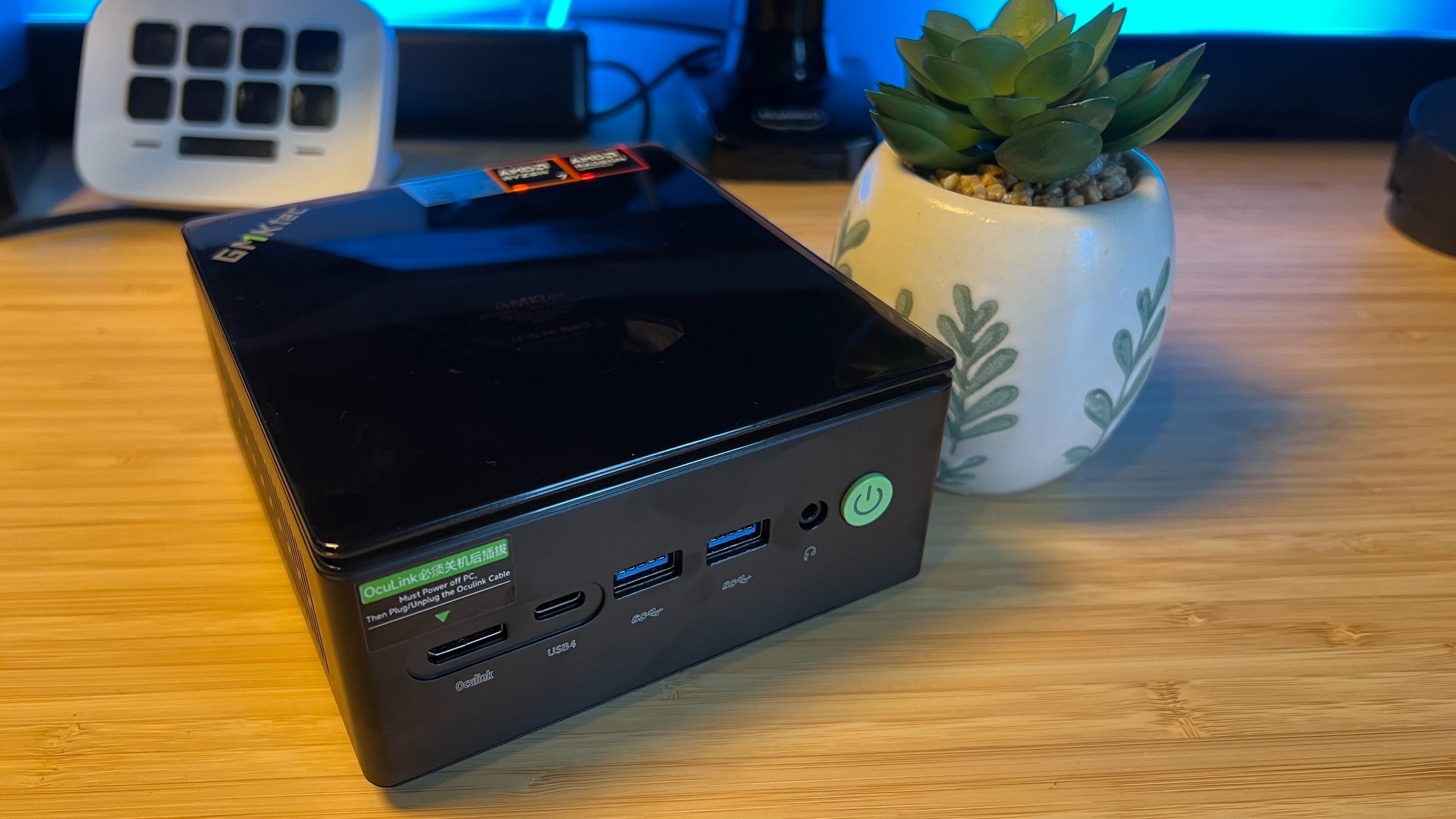 GMKTec K8 Plus mini PC on a wooden desk with a pot plant