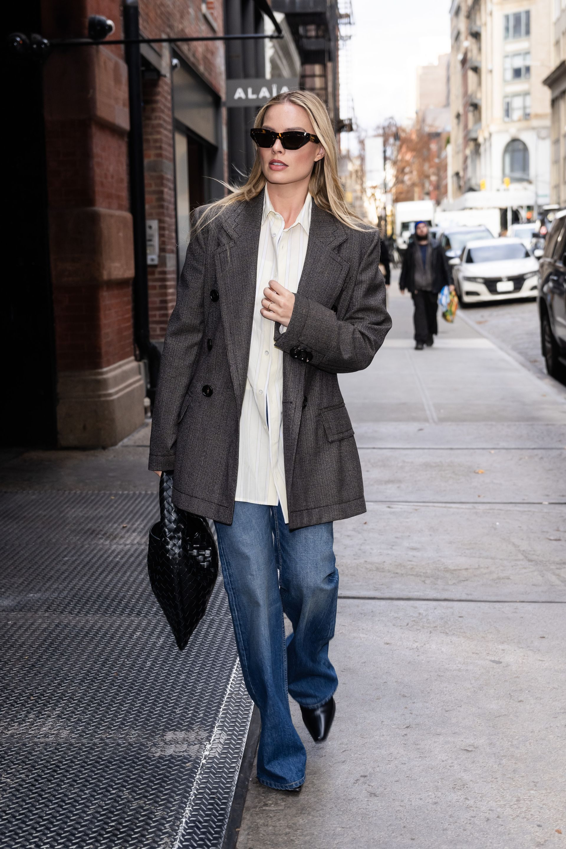 Margot Robbie wears jean, pointed toe boots and a blazer in New York.