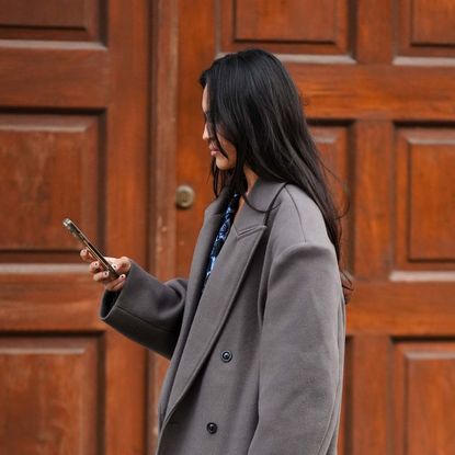 woman with long brunette hair looking at her phone Getty Images 1613721047