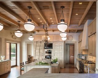 Rustic open-plan kitchen with mixed wood elements and warm wood ceiling with beams and staggered pendant lights