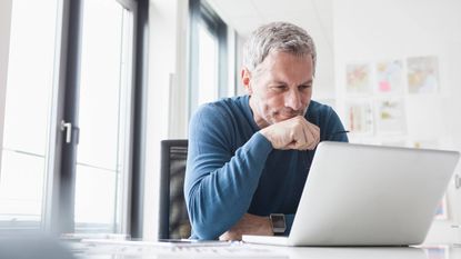 A man thinks as he looks at his laptop screen.