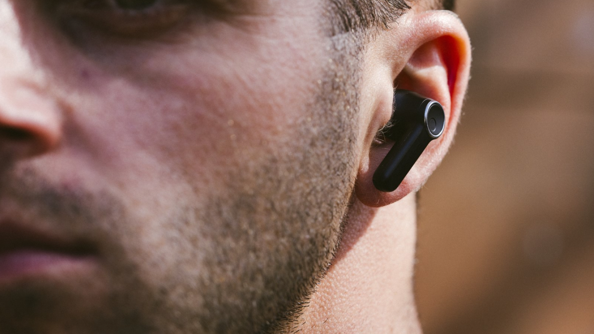 A close up of a stubbly man wearing Cambridge Audio Melomania A100 in black