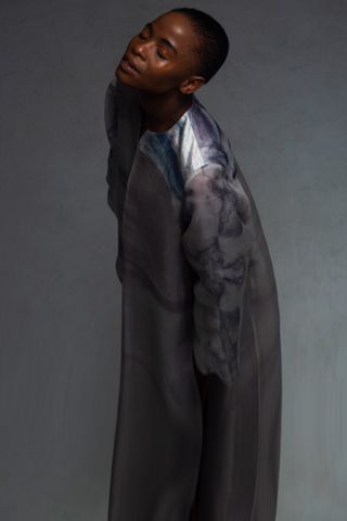 A model wearing a garment dyed with Coelicolor bacterial pigment extract, the result being a marbled effect of pink, purple and blue
