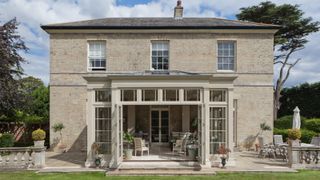 orangery to rear of large house painted in similar shade to the stonework of the house