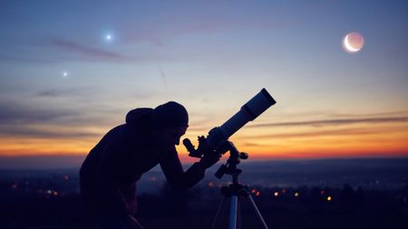 Image shows a man using one of the best telescopes for seeing planets set against a night sky