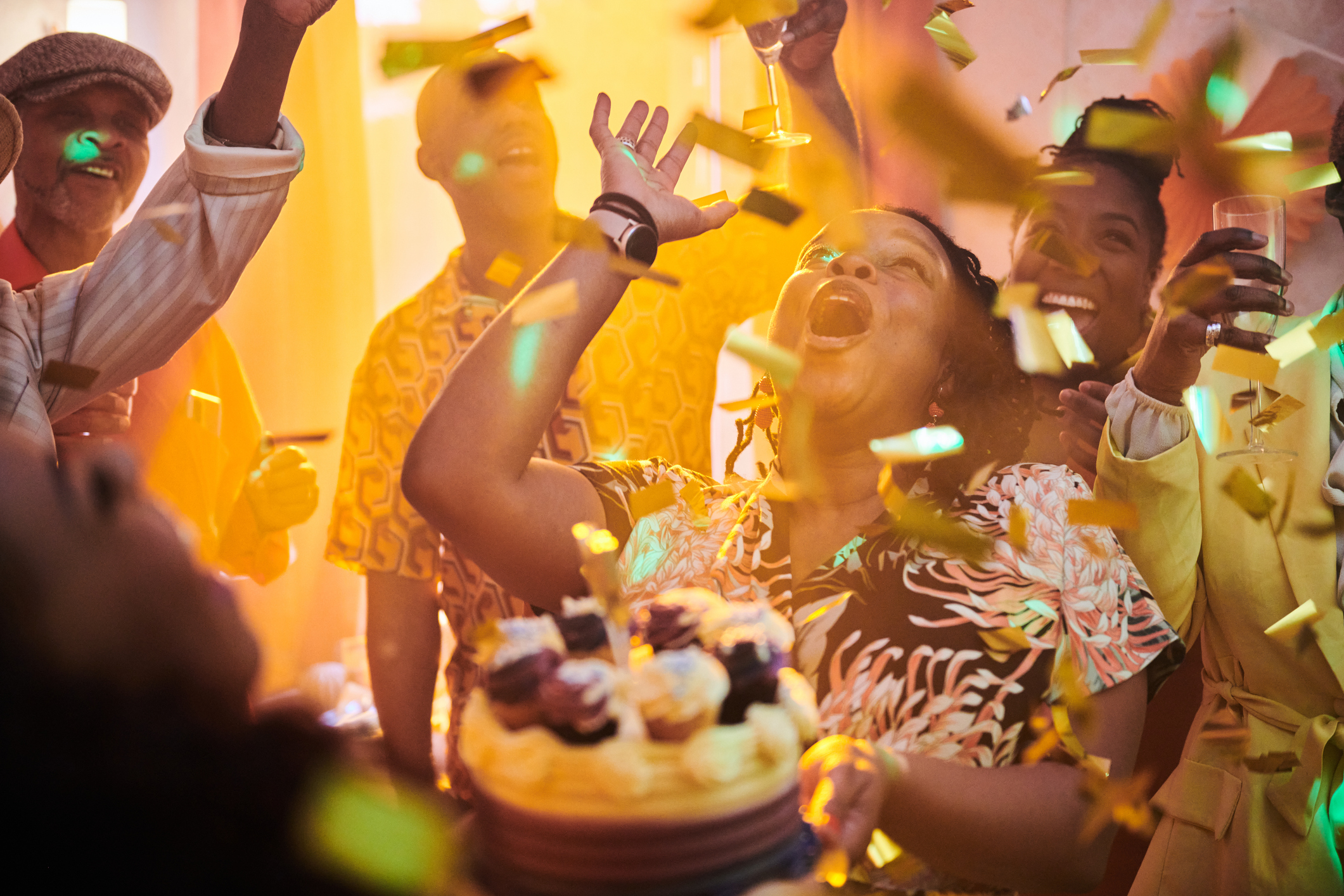A birthday celebration at home with people relaxing, having fun and enjoying themselves. Woman holding birthday cake.