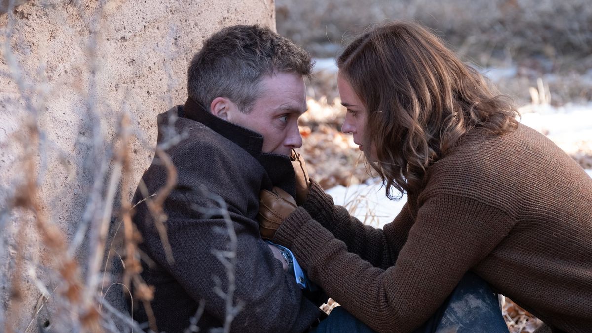 Emily Blunt holds Cillian Murphy by the collar leaning against a rock in Oppenheimer