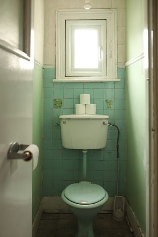 A dated bathroom with an avocado toilet