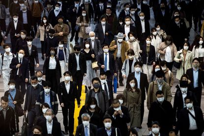 People wearing masks on crowded Tokyo street.