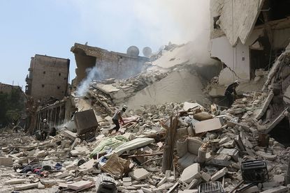 Rescue workers search for victims after a barrel bombing in Aleppo, Syria