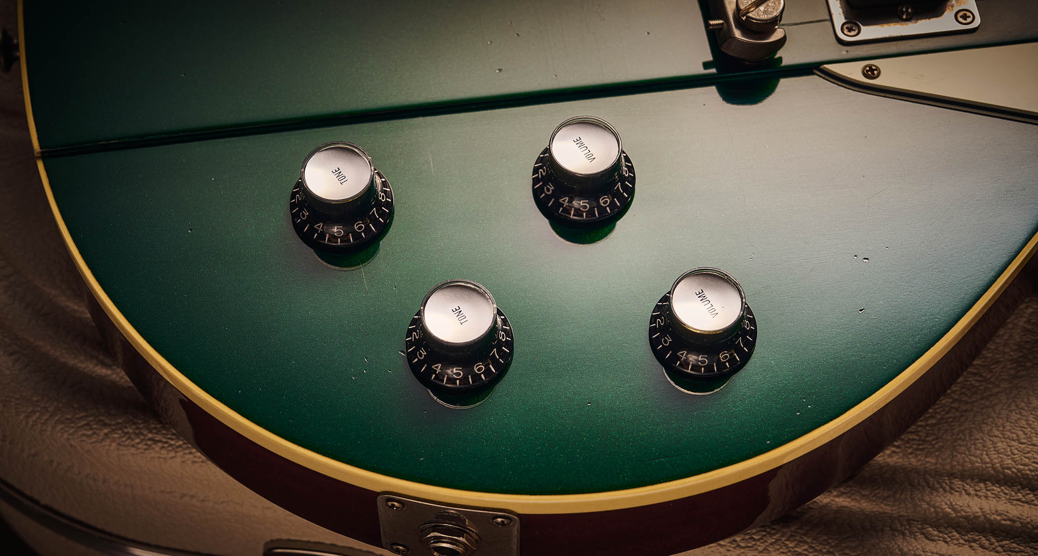 Ivison Dakota Standard in Cadillac Green photographed against its cream-covered Hiscox hard-shell guitar case.