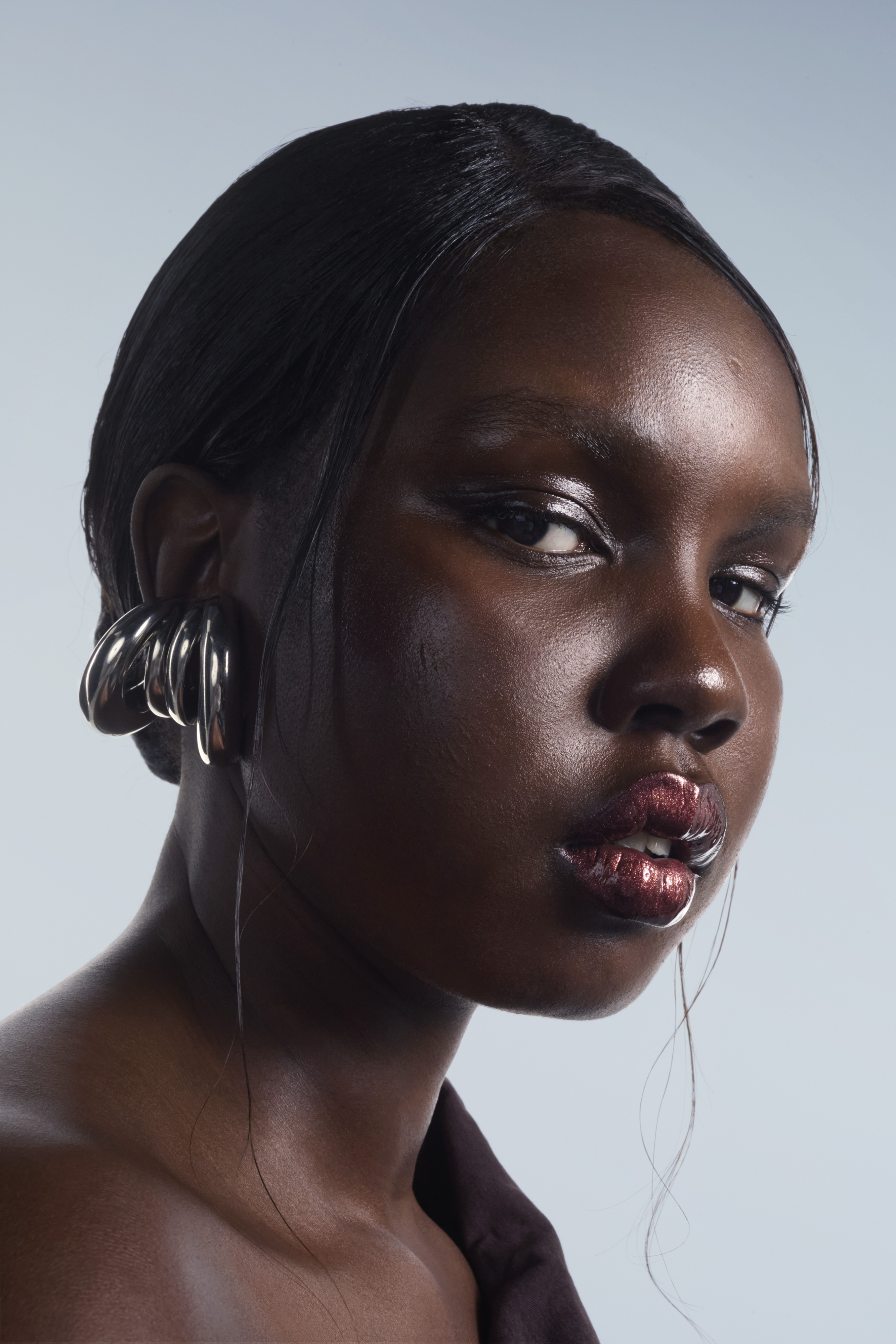 Model wearing metallic eyeshadow and earrings with a glossy lip