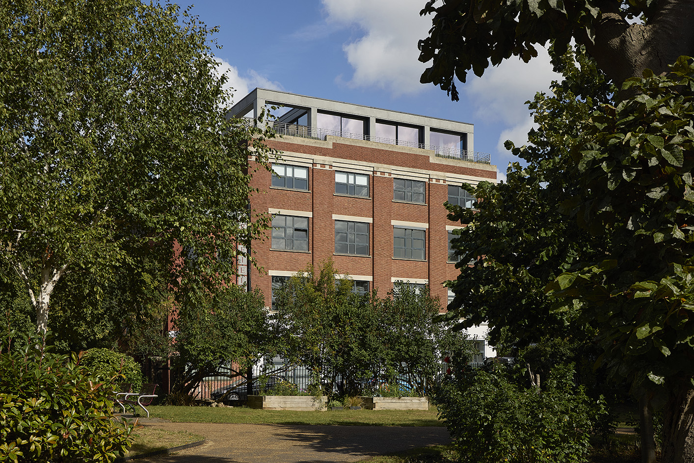 Clerkenwell Rooftop apartment in London, showing minimalist concrete and large openings with terrace and views out to urban views with green