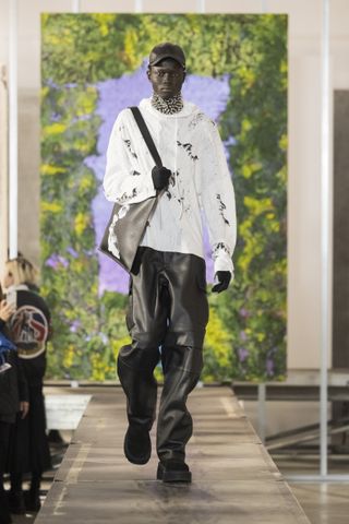 Man on runway with studded collar, white hoodie and trousers