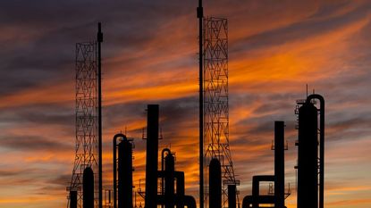 Oil refinery plant silhouetted against sunset