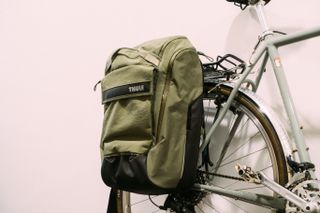 A green pannier mounted to a green bike against a white wall