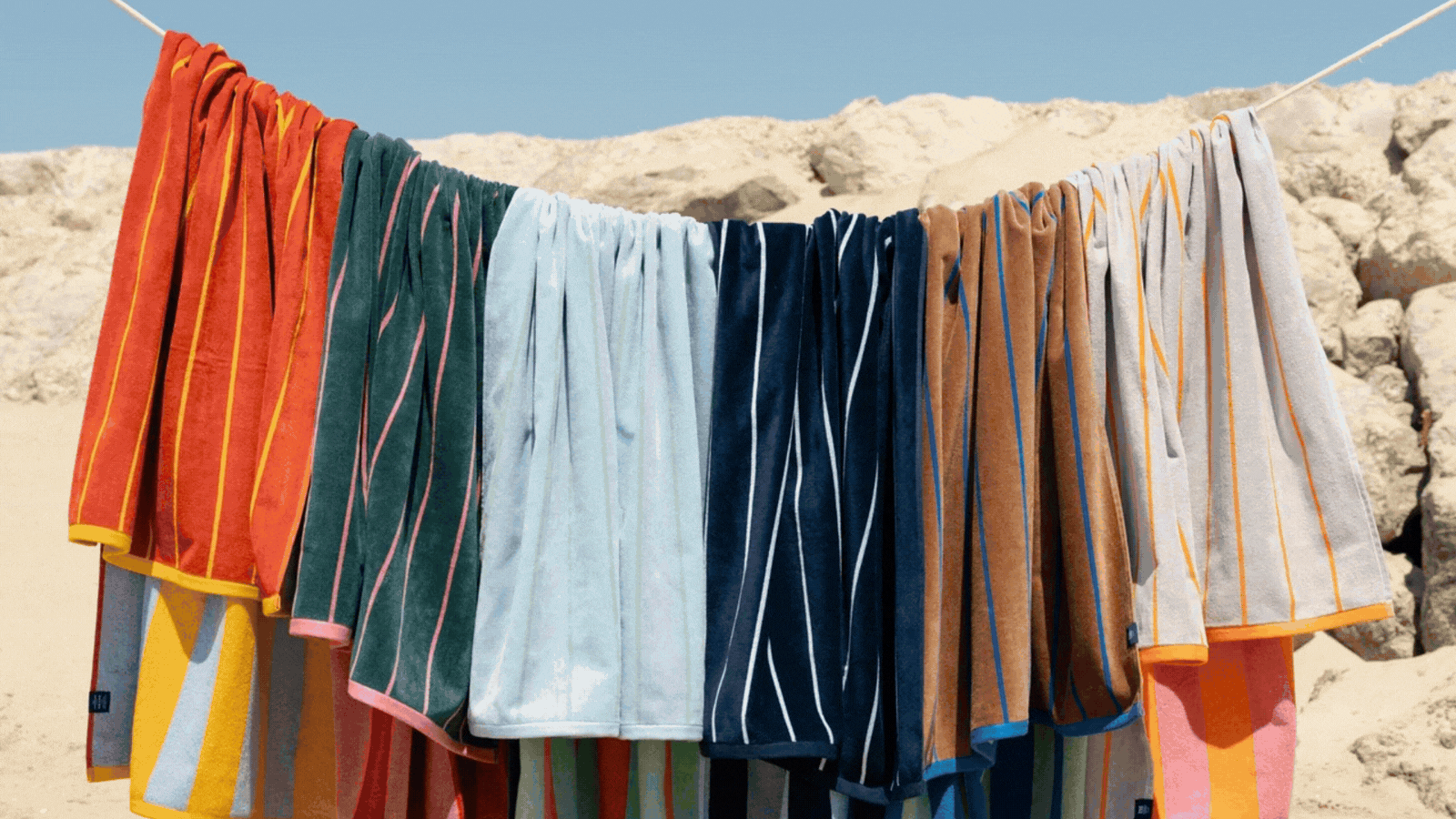 A rotating gif showing colorful, striped or printed beach towels in the sun.