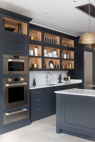 An example of kitchen storage ideas showing a dark gray kitchen with open shelving and an island with white worktops