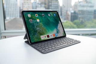 Bästa surfplatta: En iPad Pro 11 (2018) står öppnad på ett vitt skrivbord med ett tangentbord fäst på surfplattan. I bakgrunden ses ett stort fönster med en stad utanför.
