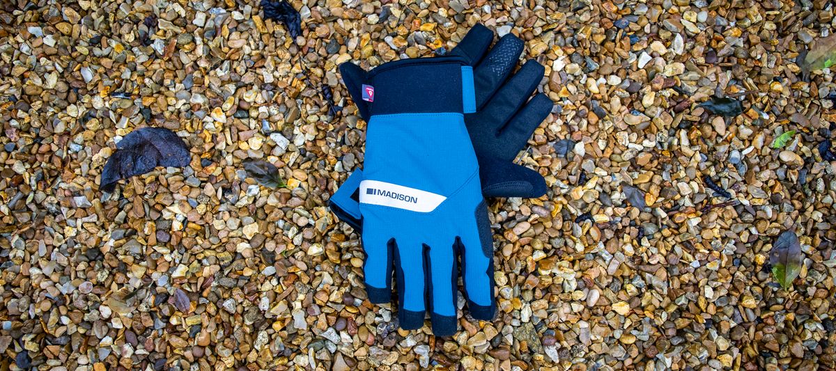 A pair of blue Madison DTE waterproof gloves on gravel 