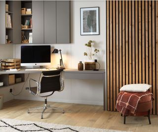 A modern home office with a corner desk and slatted wall panels 