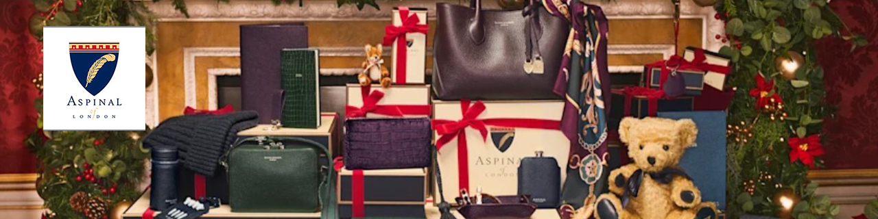 Aspinal of london logo top left with a wide image of bags and teddys with a christmas tree behind it 