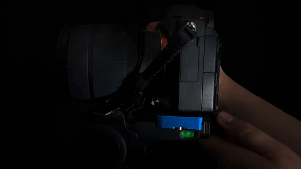 A close-up of a camera held in a dark setting, revealing metal and plastic components with a small level indicator