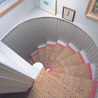 Curved staircase showing white stairs and a jute stair runner.
