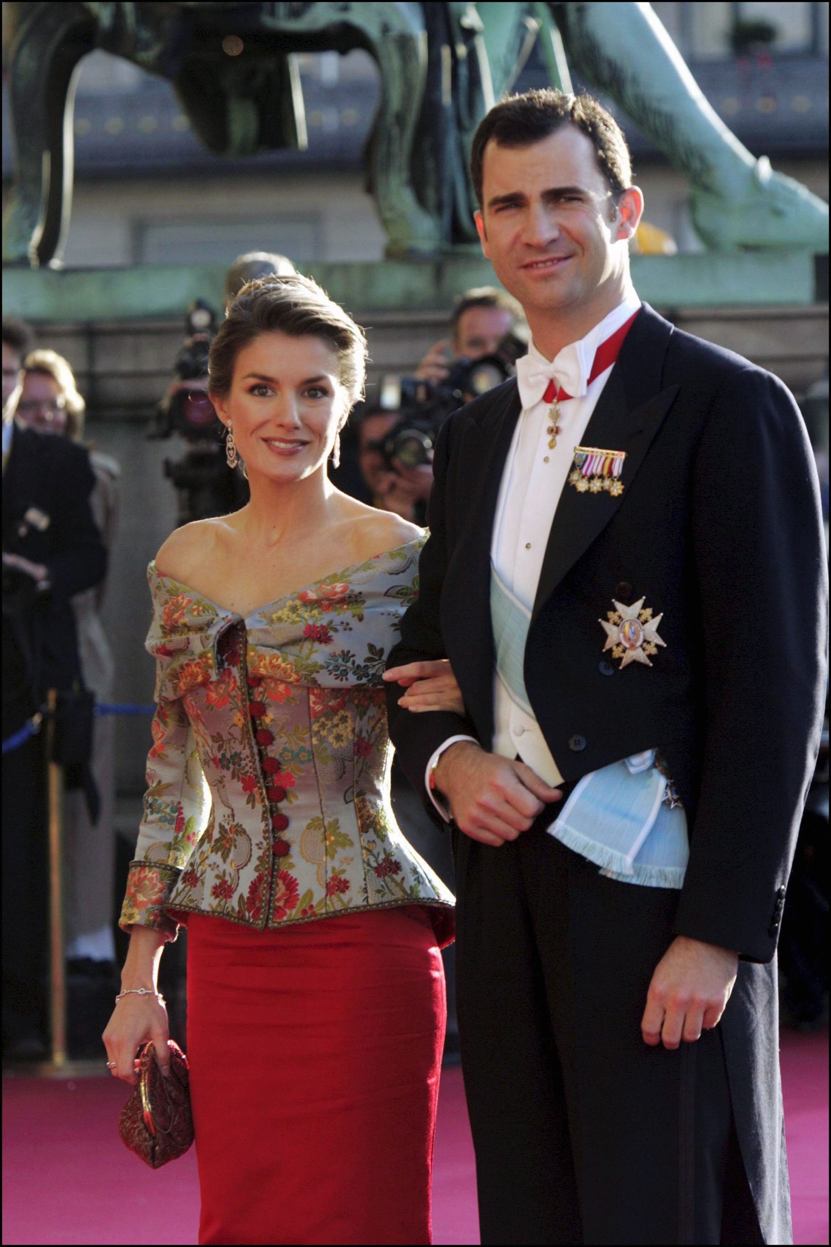 Queen Letizia and King Felipe linking arms on a red carpet at the pre-wedding dinner for Queen Mary and King Frederik in 2004