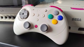 Close up of Gulikit Elves 2 Pro leaning against white Sega Saturn next to Sony PVM CRT TV.