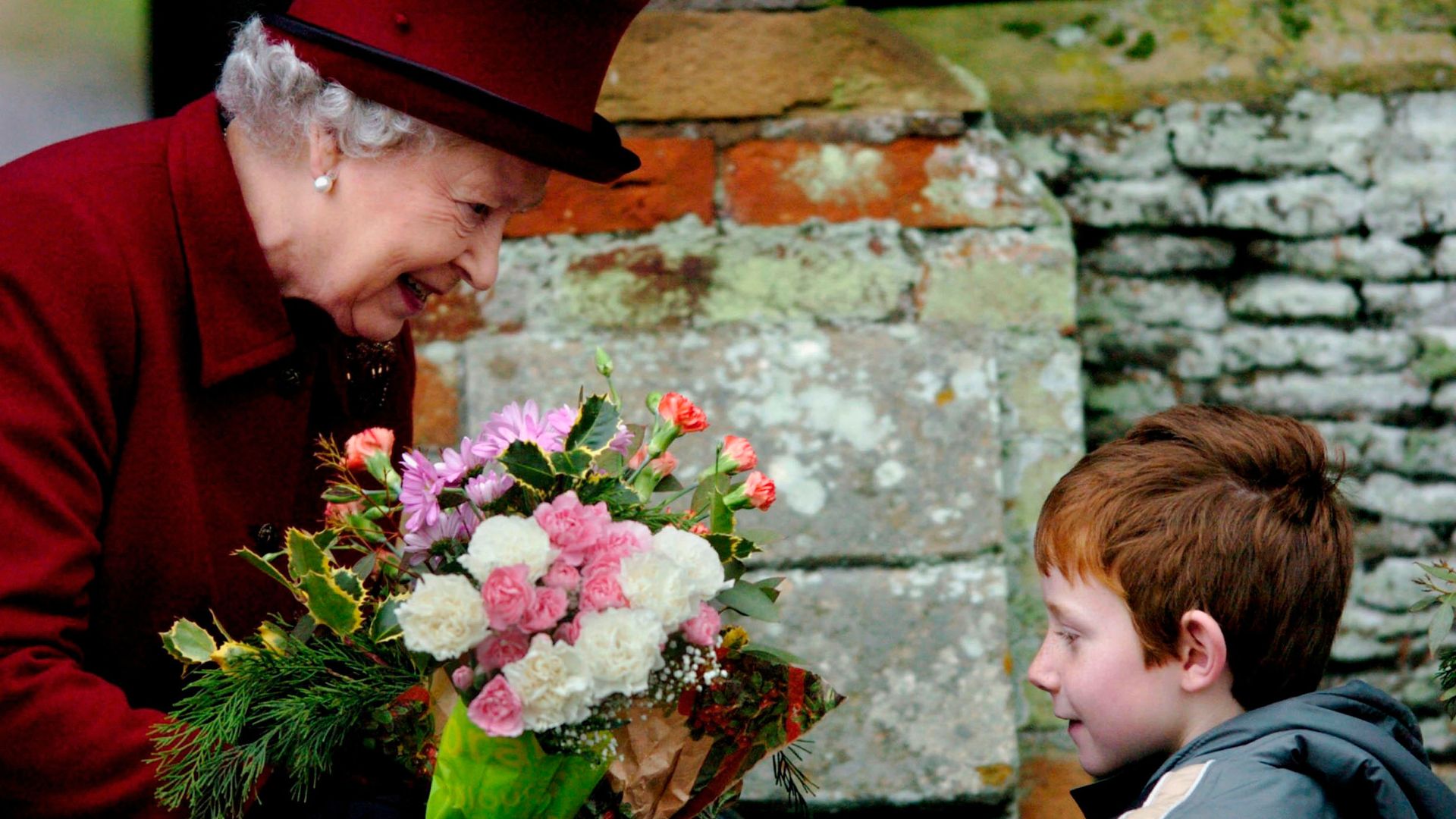 Queen Elizabeth II smiles as she is given flowers after attending St Mary Magdalene Church on January 1, 2006