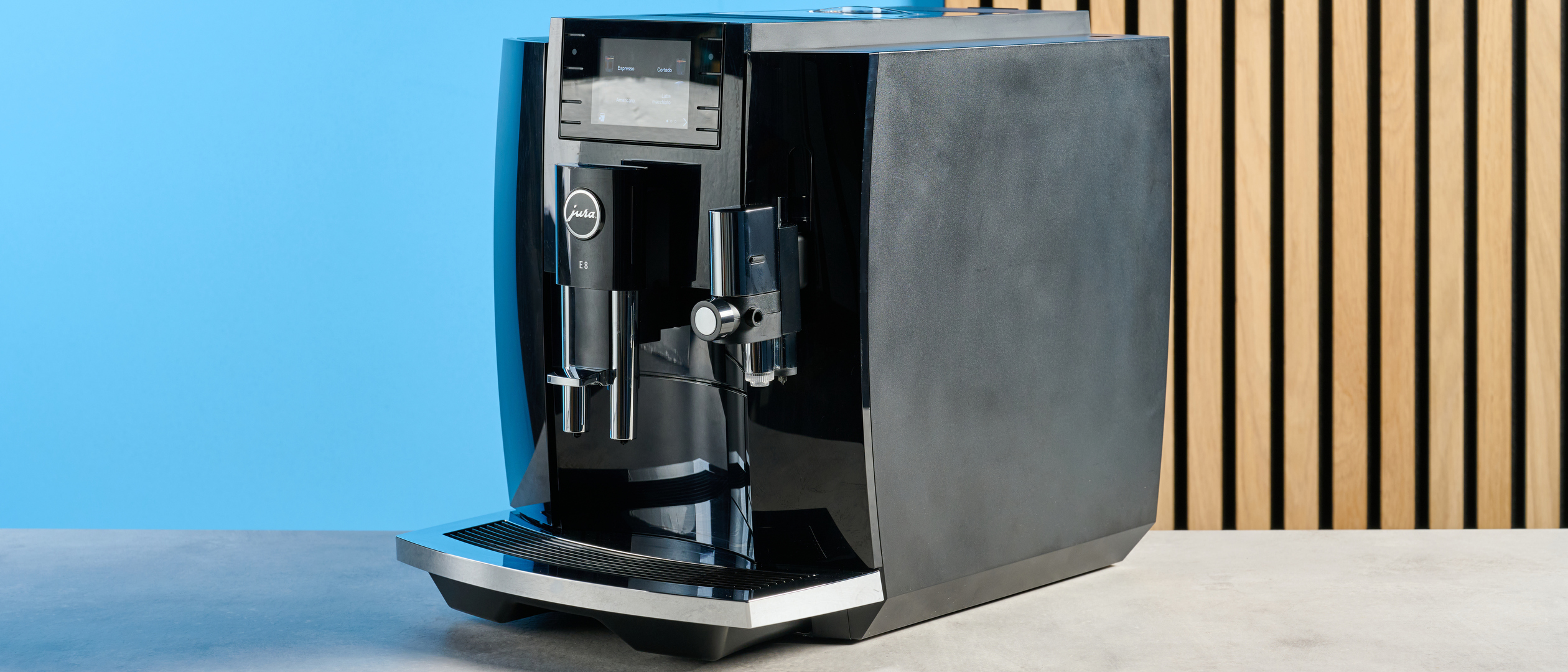 the jura E8 automatic coffee machine in piano black with a 64 ounce water tank, screen, and jura logo on the front
