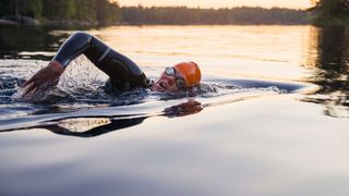 Woman wearing goggles and hat swimming in lake