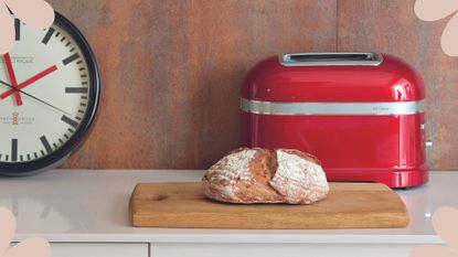 Red toaster in a contemporary wooden kitchen with a fresh loaf of bread to show why how to clean a toaster is an essential chore