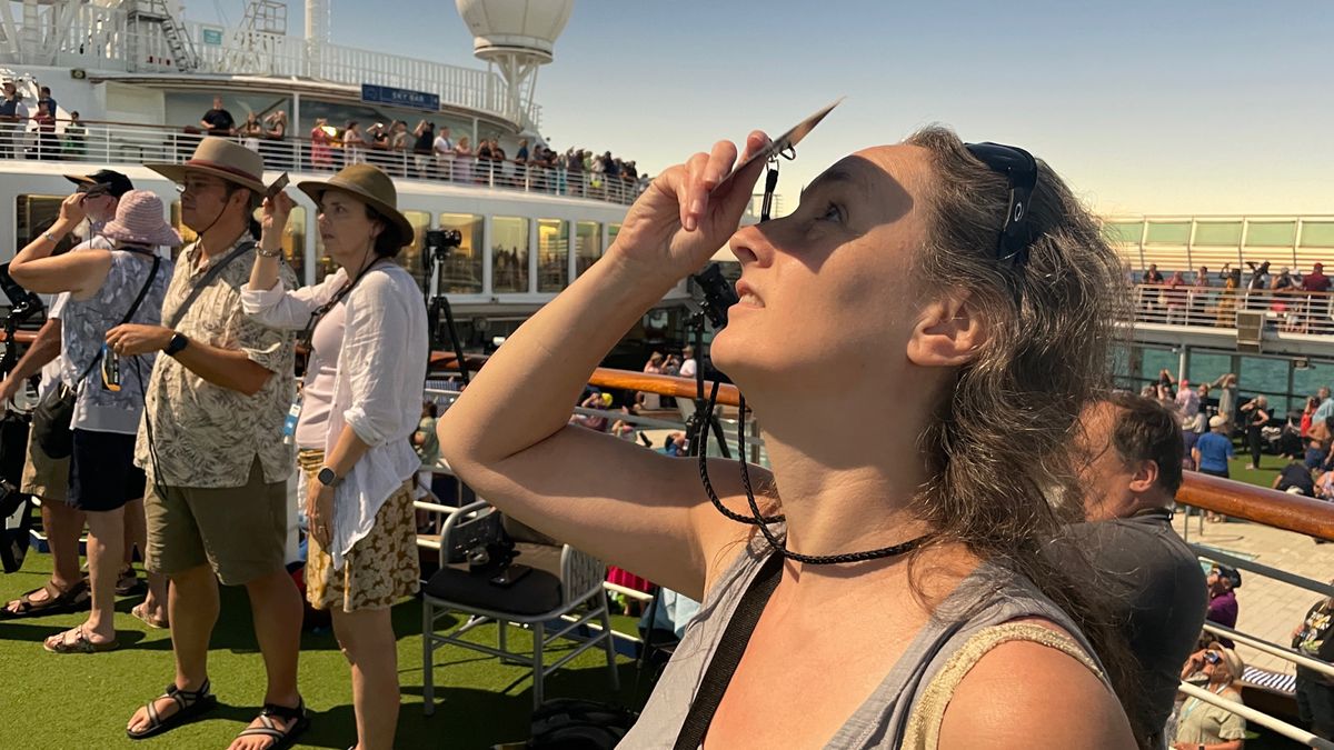 a woman views a solar eclipse through eclipse glasses