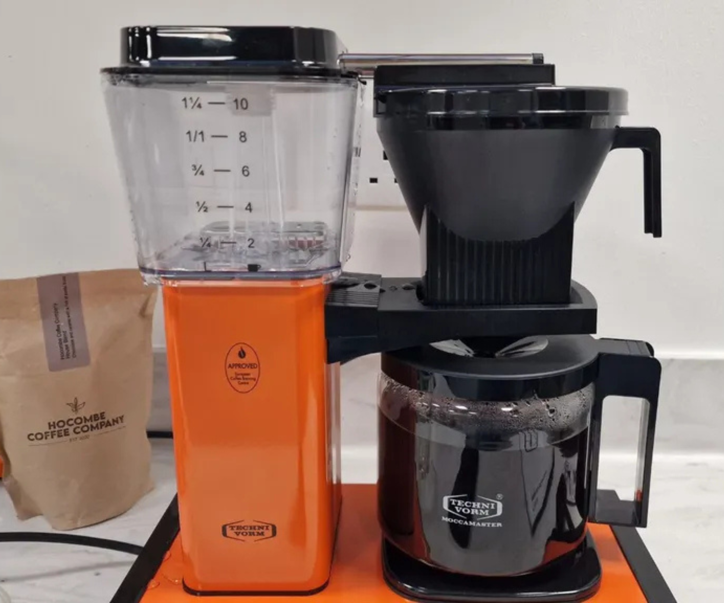 An orange Moccamaster Filter Coffee Maker brewing coffee in our test kitchen