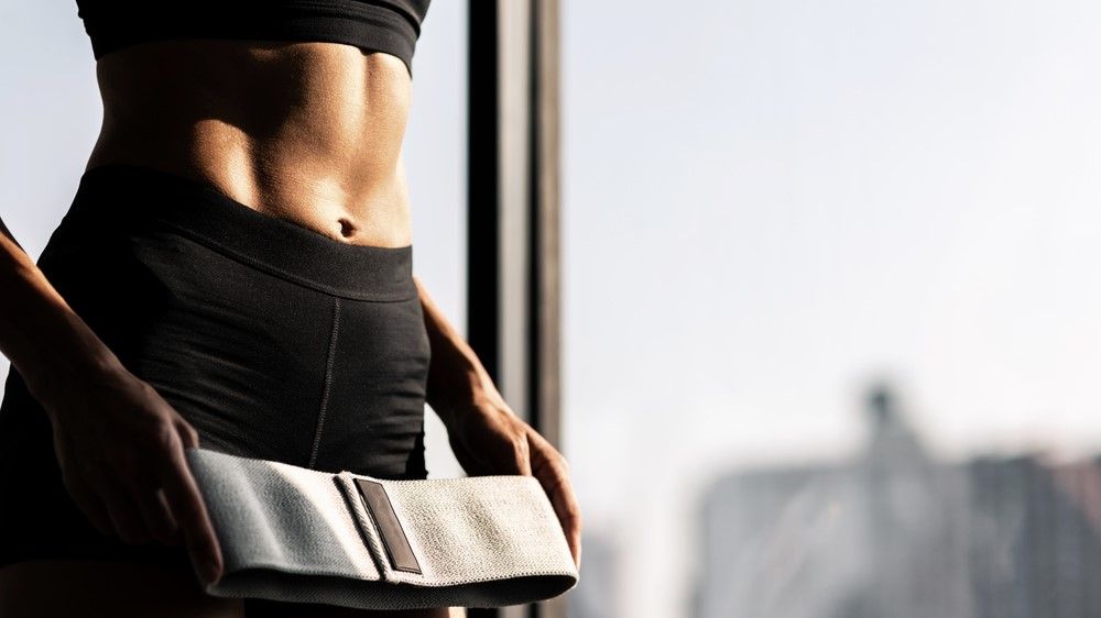 a photo of a woman with abs holding a resistance band