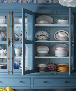 Blue kitchen hutch filled with a vintage china collection