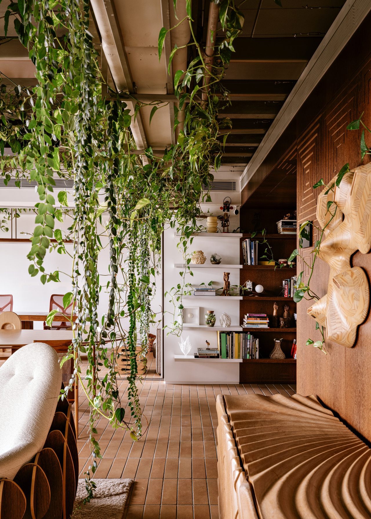 A living room with trailing vines beside a textured wood credenza and a sofa chair