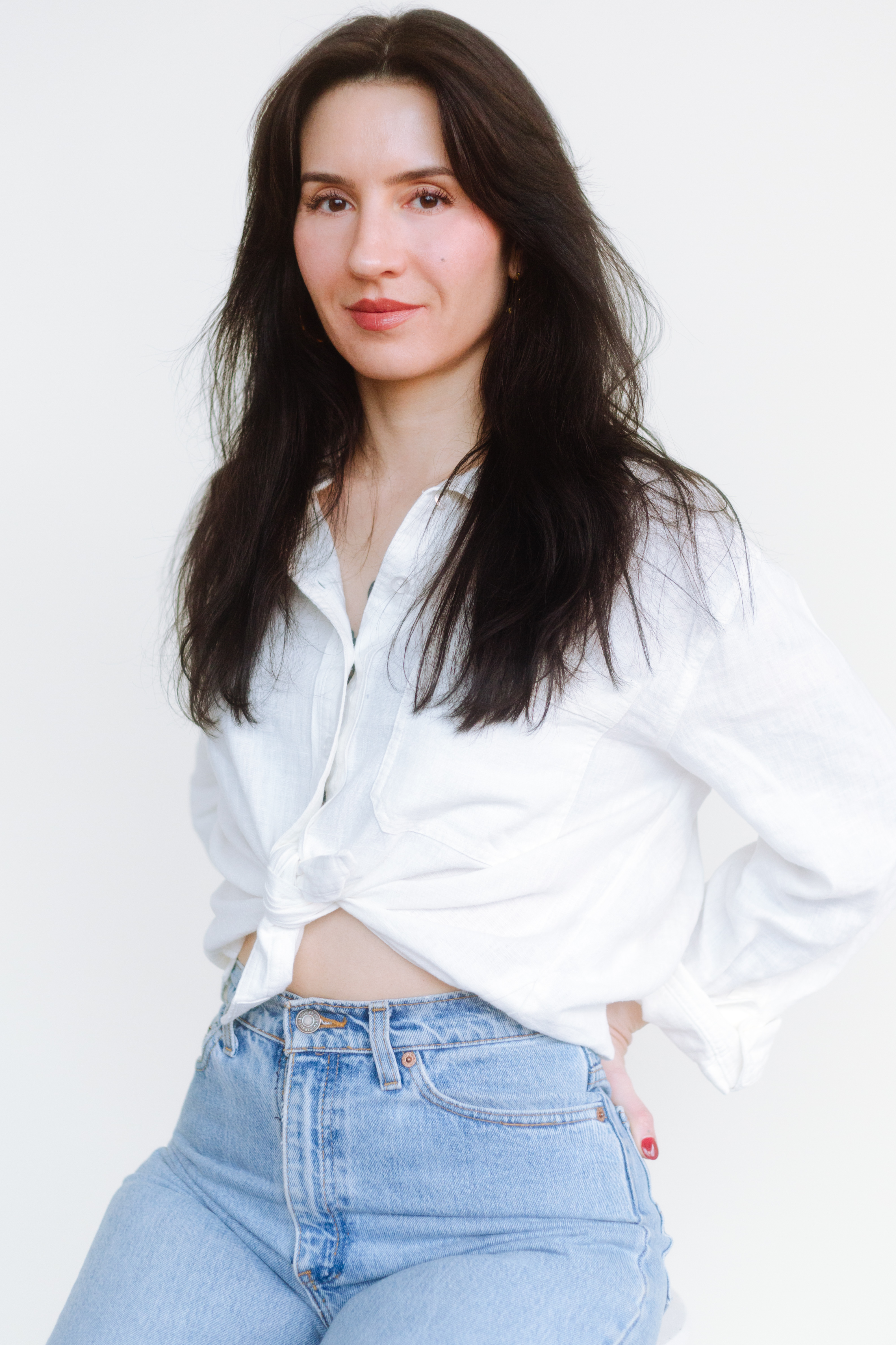 a white woman with dark hair in a white shirt and blue jeans