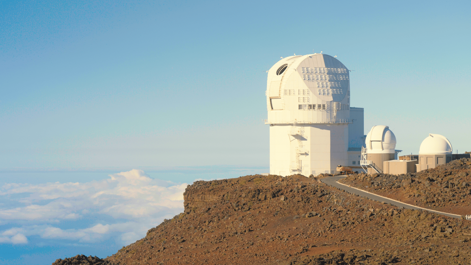 A white domed structure on top of a dirt mountain. It appears to be above the clouds in the distant sky.