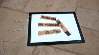 Huion L4S light pad with film negatives on a beige stone slab surface