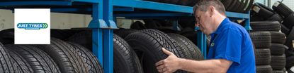 Man selecting tyre from tyre rack with Just Tyres logo in top left corner