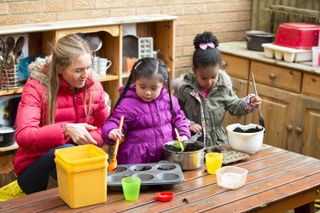 mud kitchen ideas: two girls making mud pies