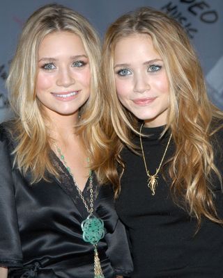 The Olsen twins with long, lightly curled, blonde hair.