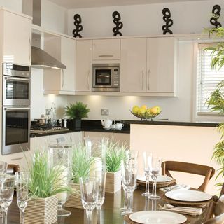 kitchen area with white kitchen units with dinner table and chairs and white wall