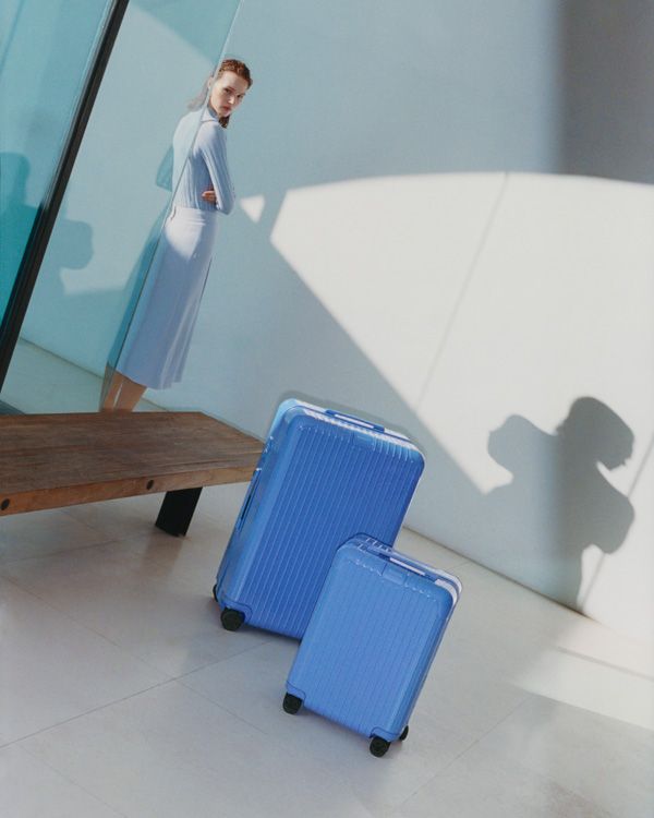A sea blue minimalist cabin suitacase is captured in multiple sun-lit settings.