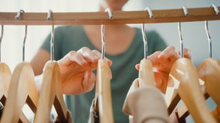 person browsing hangers in wardrobe