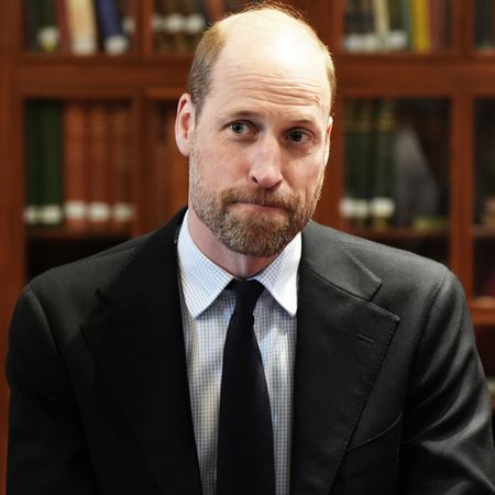 Prince William looks serious while wearing a black suit with a white shirt and a black tie