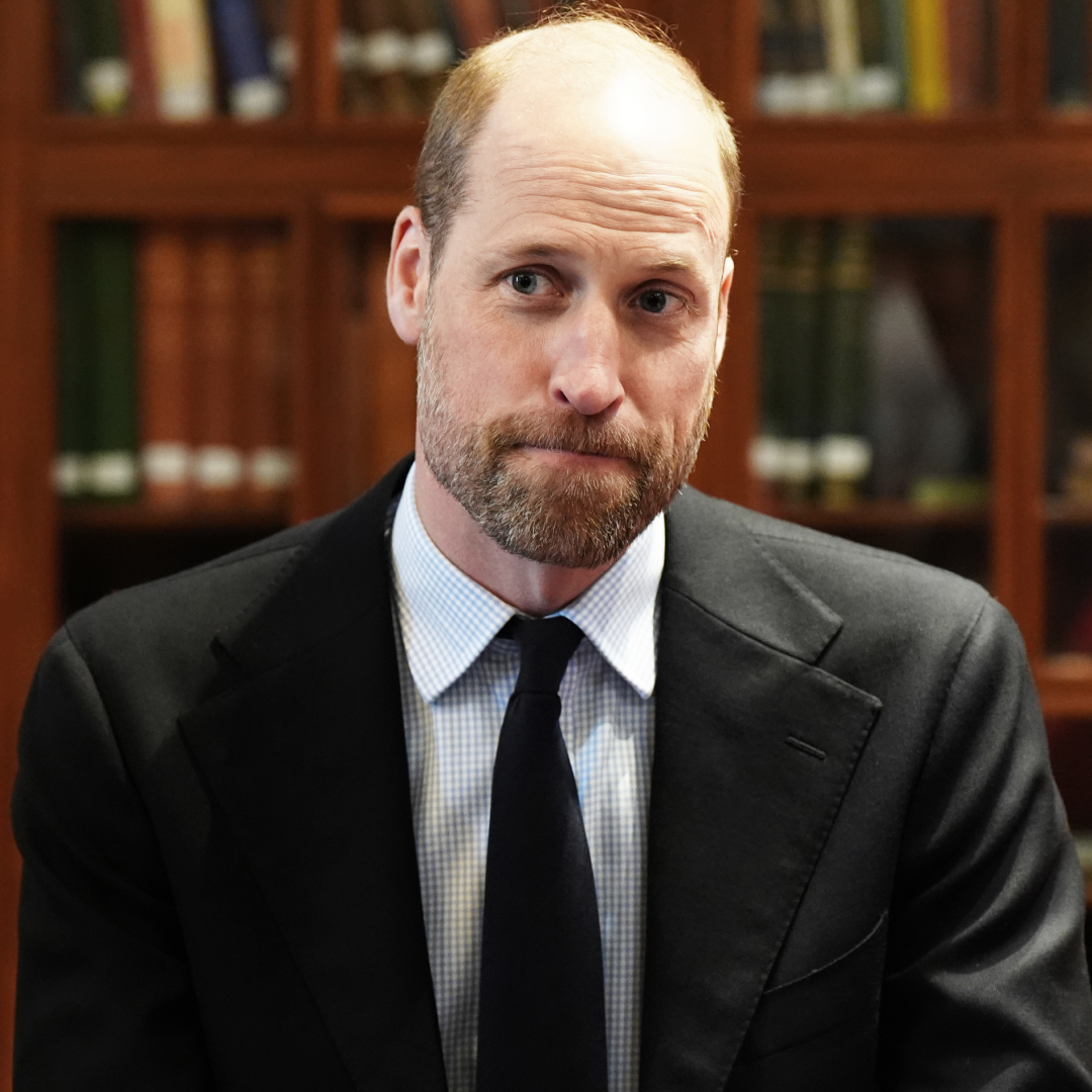 Prince William looks serious while wearing a black suit with a white shirt and a black tie
